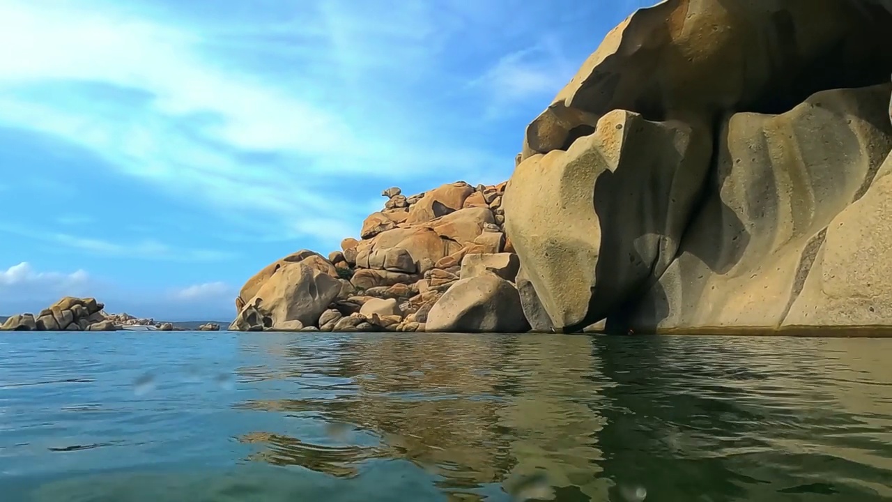 在拉维奇岛的Cala Della Chiesa海湾，半水下的粉红色花岗岩大岩石的翻拍视图与背景中的豪华船。法国科西嘉岛，慢镜头视频素材