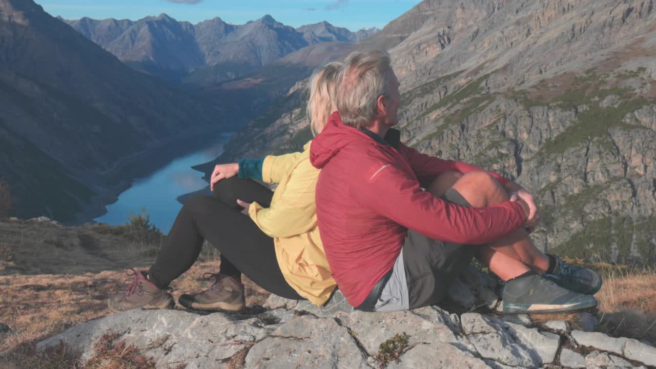 一对徒步情侣在登山山顶放松，眺望远方视频素材