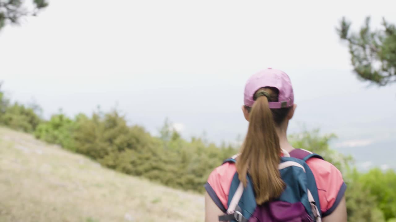 女孩在大自然中远足。背景背包客沿着森林里的小路下山。视频素材