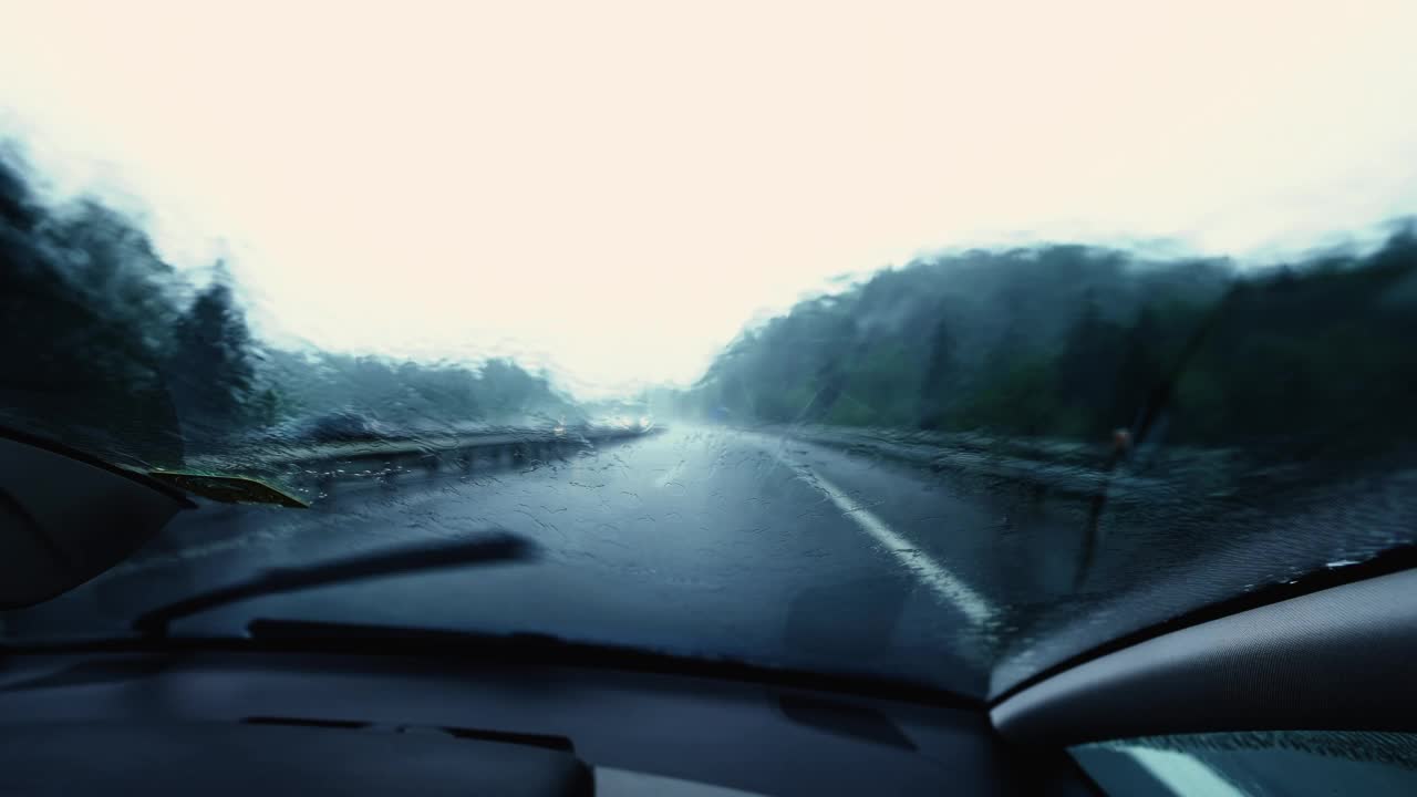 特写汽车挡风玻璃在雨中行驶。车辆高速公路在下雨时的载客量。水滴在玻璃上慢动作视频素材