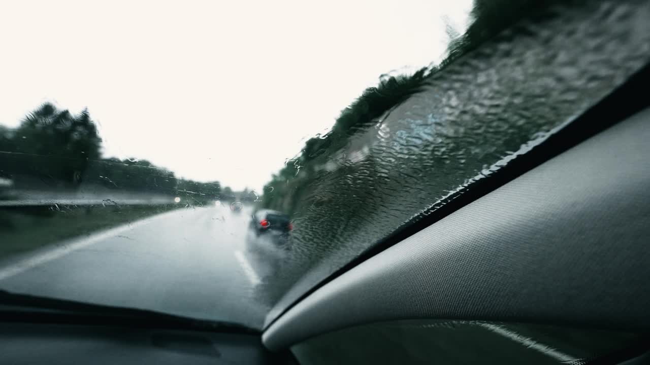 暴风雨期间高速公路上车内乘客。车辆在路上下雨的视角。挡风玻璃特写镜头视频素材