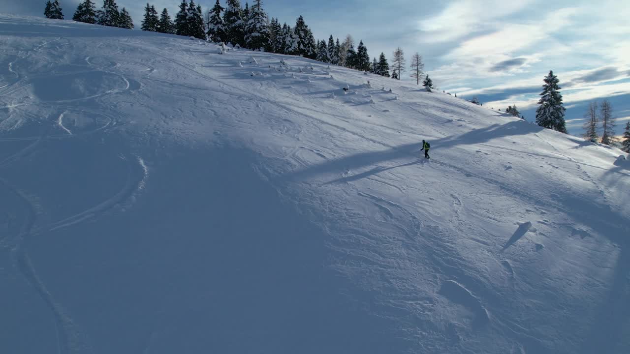 航拍:旅游滑雪者爬上雪峰，在新鲜的粉雪上转弯视频下载