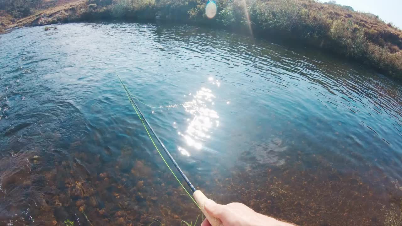 钓鱼投POV。一个人在湍急清澈的河流上飞钓鱼，然后抛了一个鱼饵视频素材