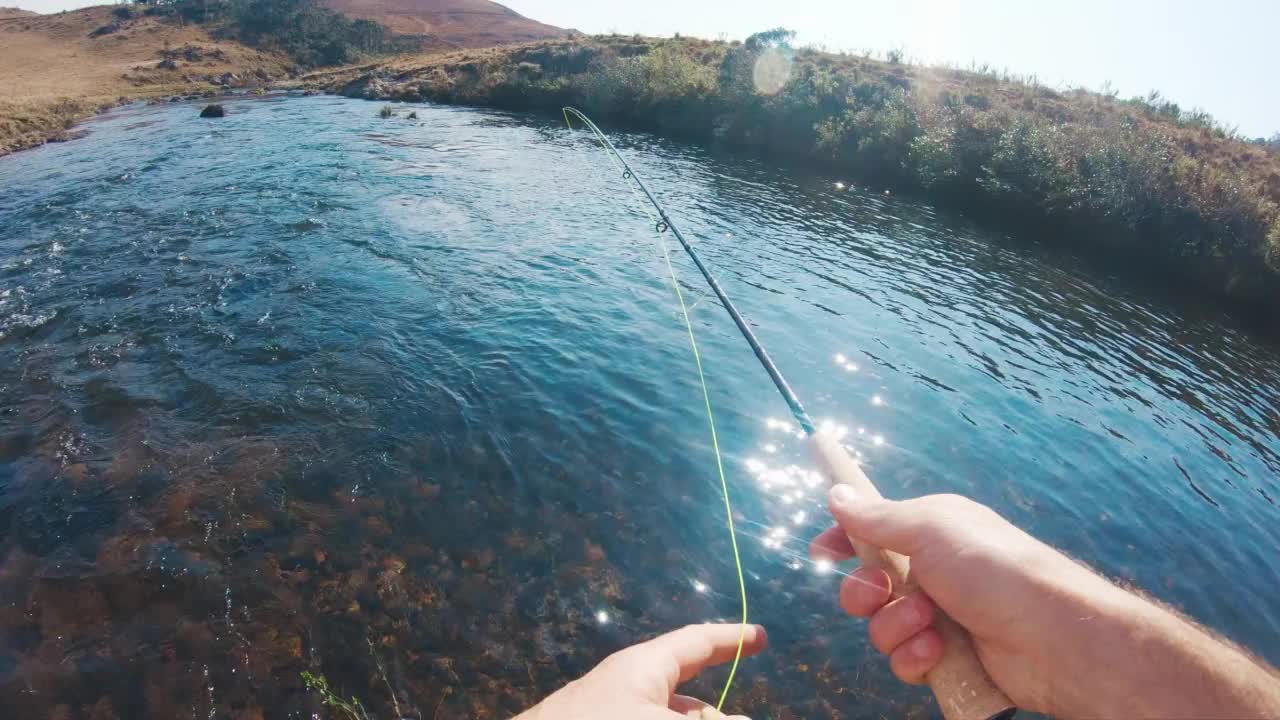 钓鱼投POV。一个人在湍急清澈的河流上飞钓鱼，然后抛了一个鱼饵视频素材