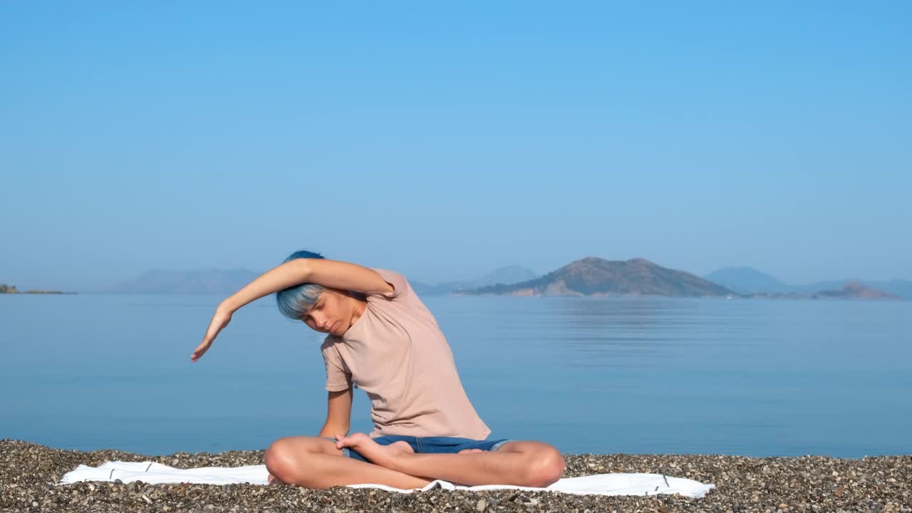 女孩伸展手瑜伽在阳光明媚的海岸。视频素材