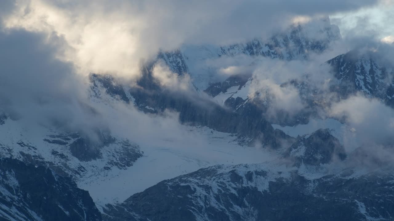 暴风雨散去后，阿尔卑斯山的山峰从云层中显现，日落时的黄金时刻视频素材