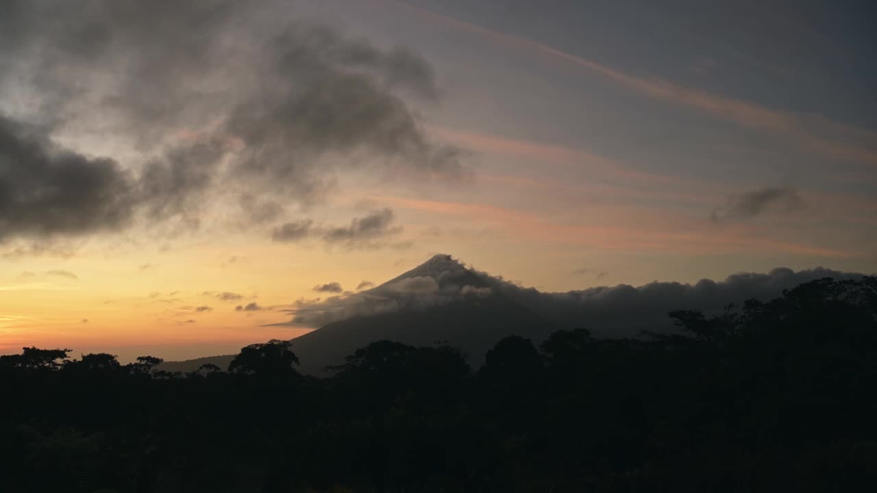 哥斯达黎加时间流逝，时间流逝的阿雷纳尔火山景观与美丽的雨林风景和戏剧性的橙色日落天空和云移动过山顶，中美洲视频素材