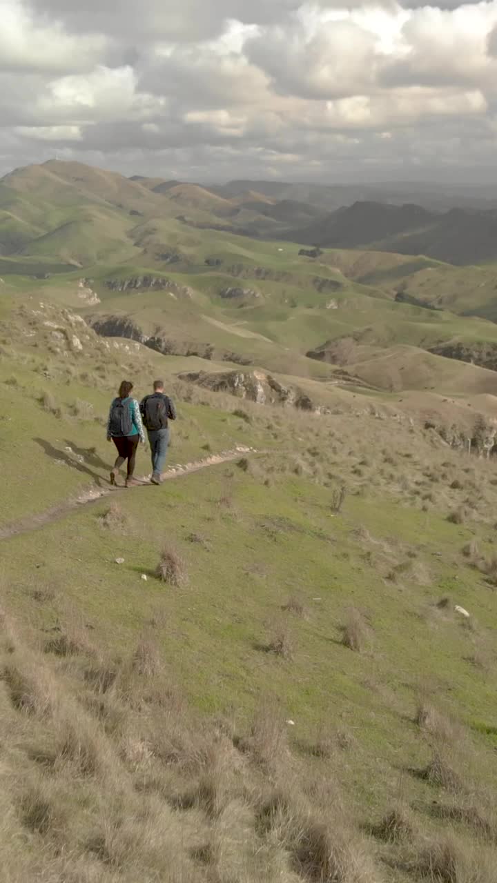 鸟瞰图上的夫妇走下山坡，拥有惊人的山峦和自然全景视频素材