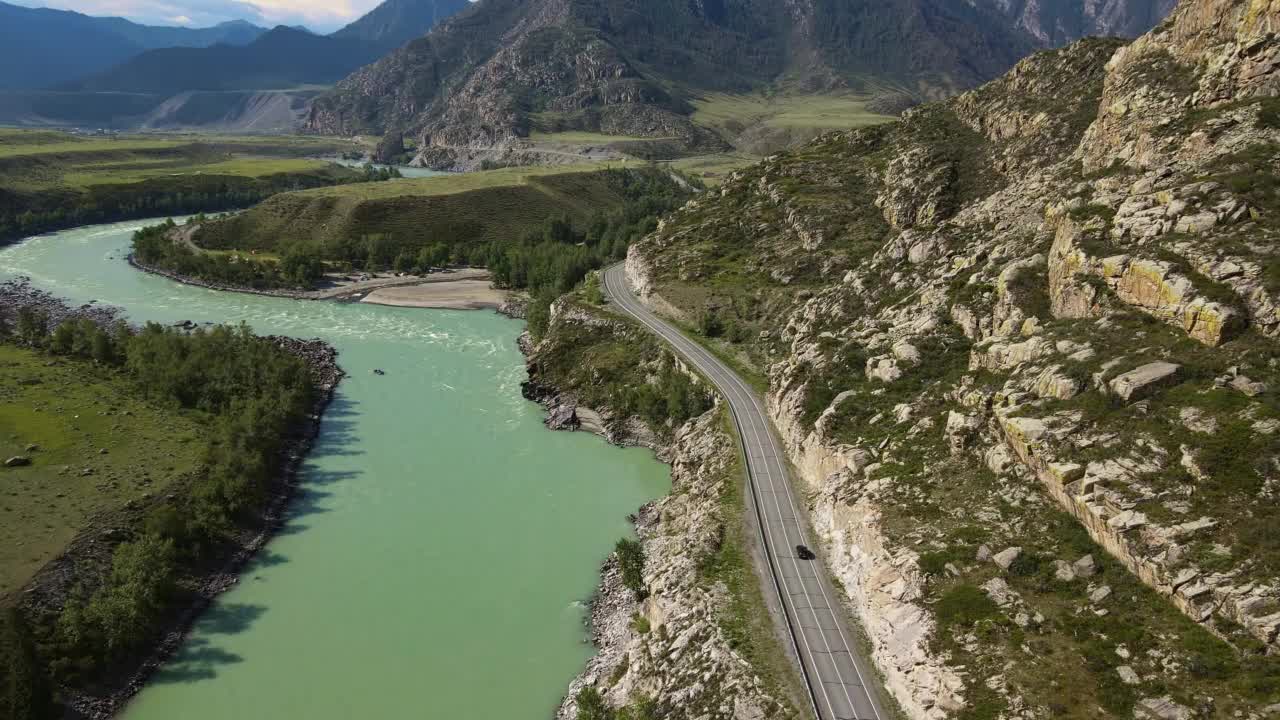 空中:蓝绿色的河流在山谷中流动，道路上有汽车视频素材