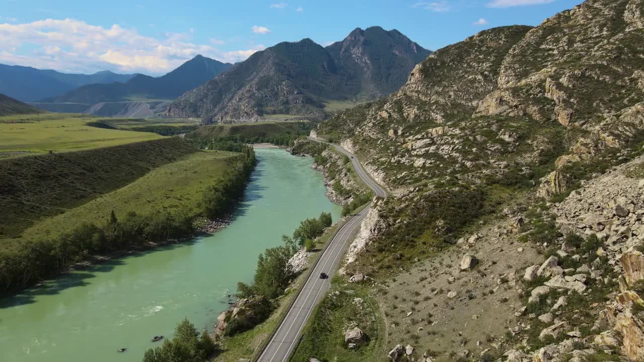 空中:蓝绿色的河流在山谷中流动，道路上有汽车视频素材