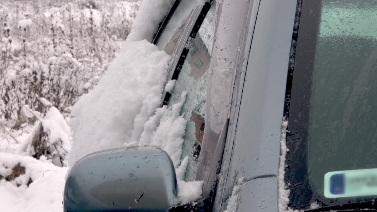 男子清理汽车挡风玻璃上的冰雪视频素材