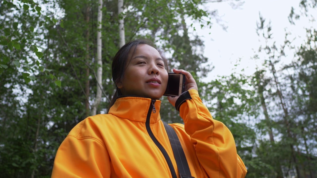 快乐的亚洲女人在森林里接电话视频素材