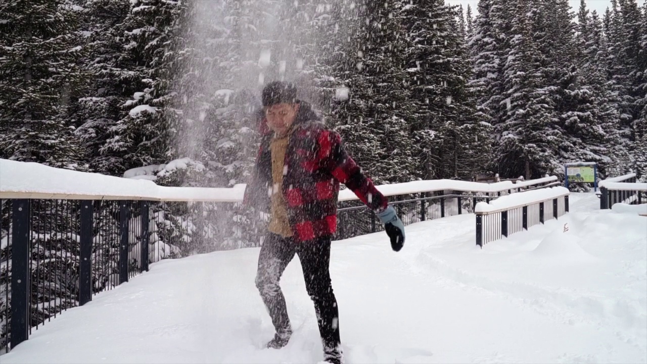 一个穿着红色外套的人在雪地里玩耍和摆姿势视频下载