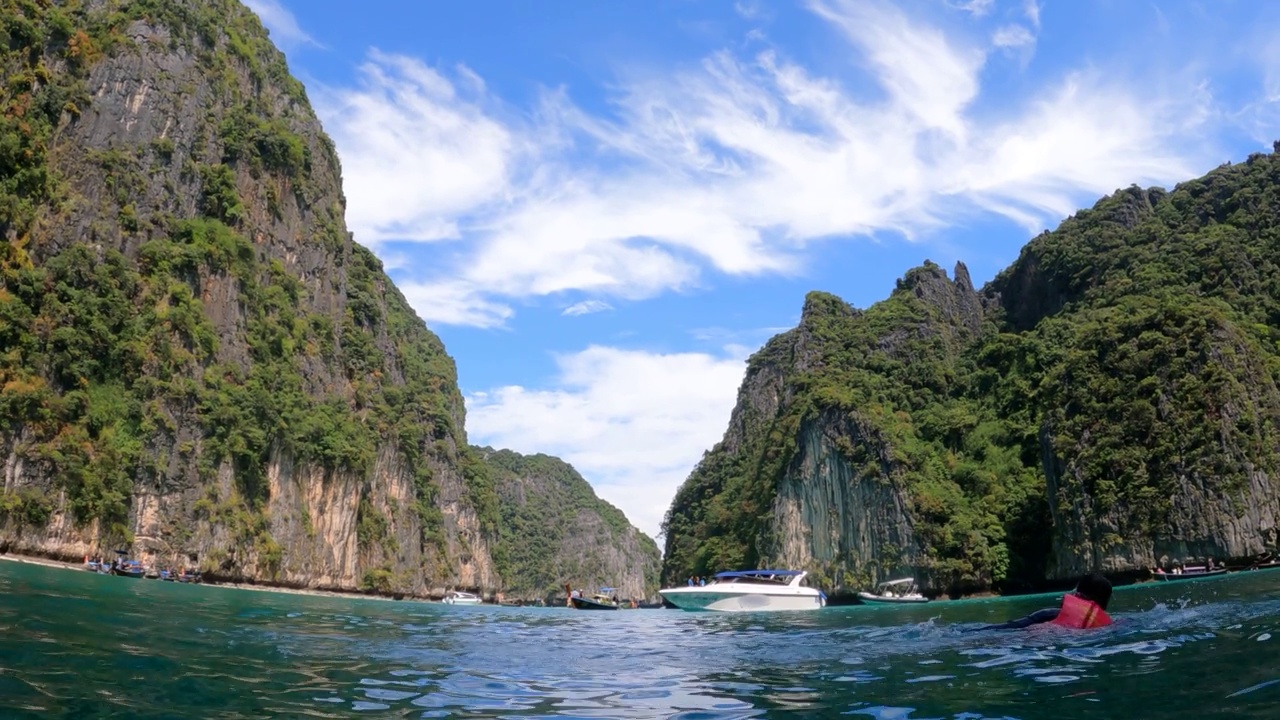 热带岛屿与海洋蓝色的海水在皮披群岛的皮莱泻湖，泰国甲米自然景观与男子游客游泳视频素材