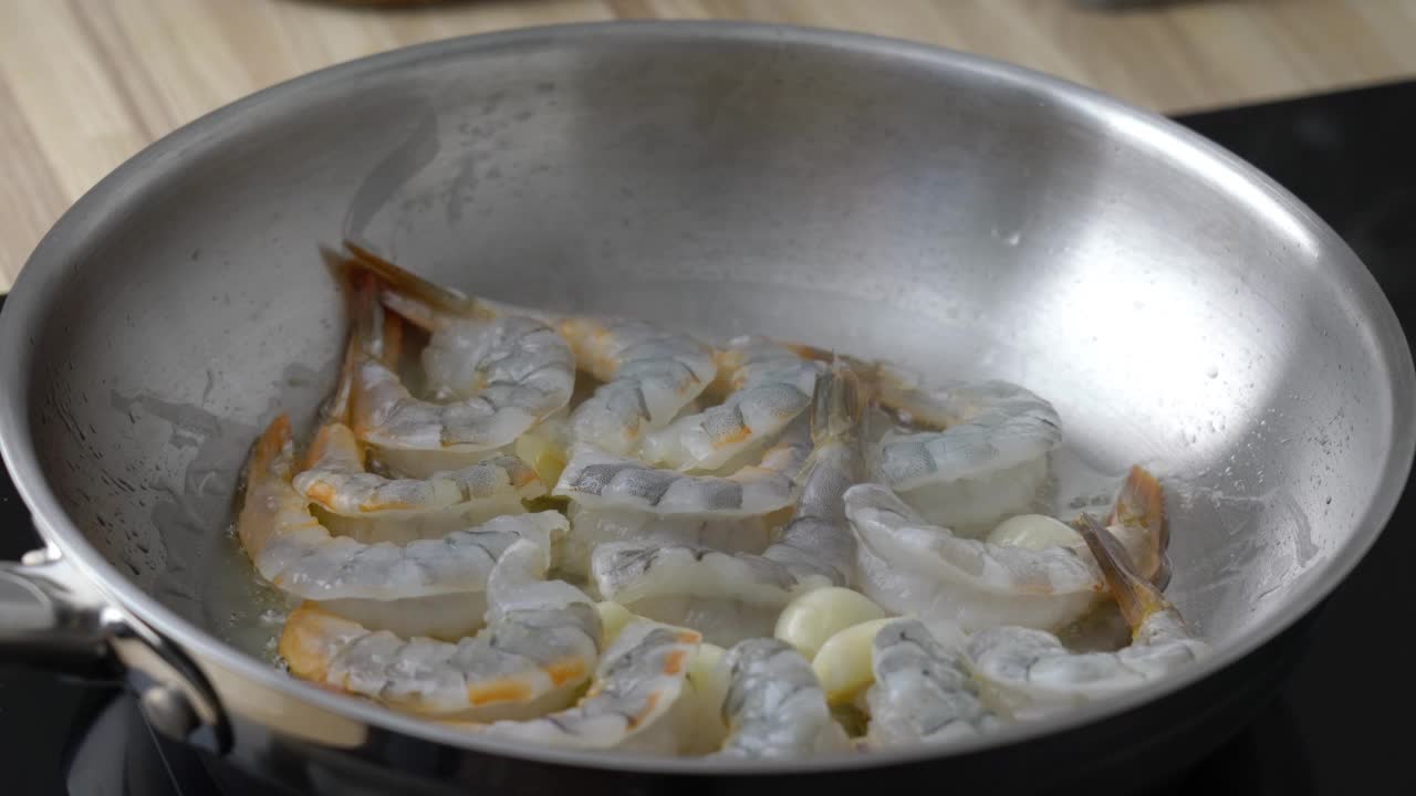 在平底锅上手工搅拌虾和海鲜。生酮餐炸虾生酮饮食，准备酱料意大利面，海鲜虾在金属煎锅中滋滋作响，热平底锅油炸富含胆固醇的旧石器食物视频下载