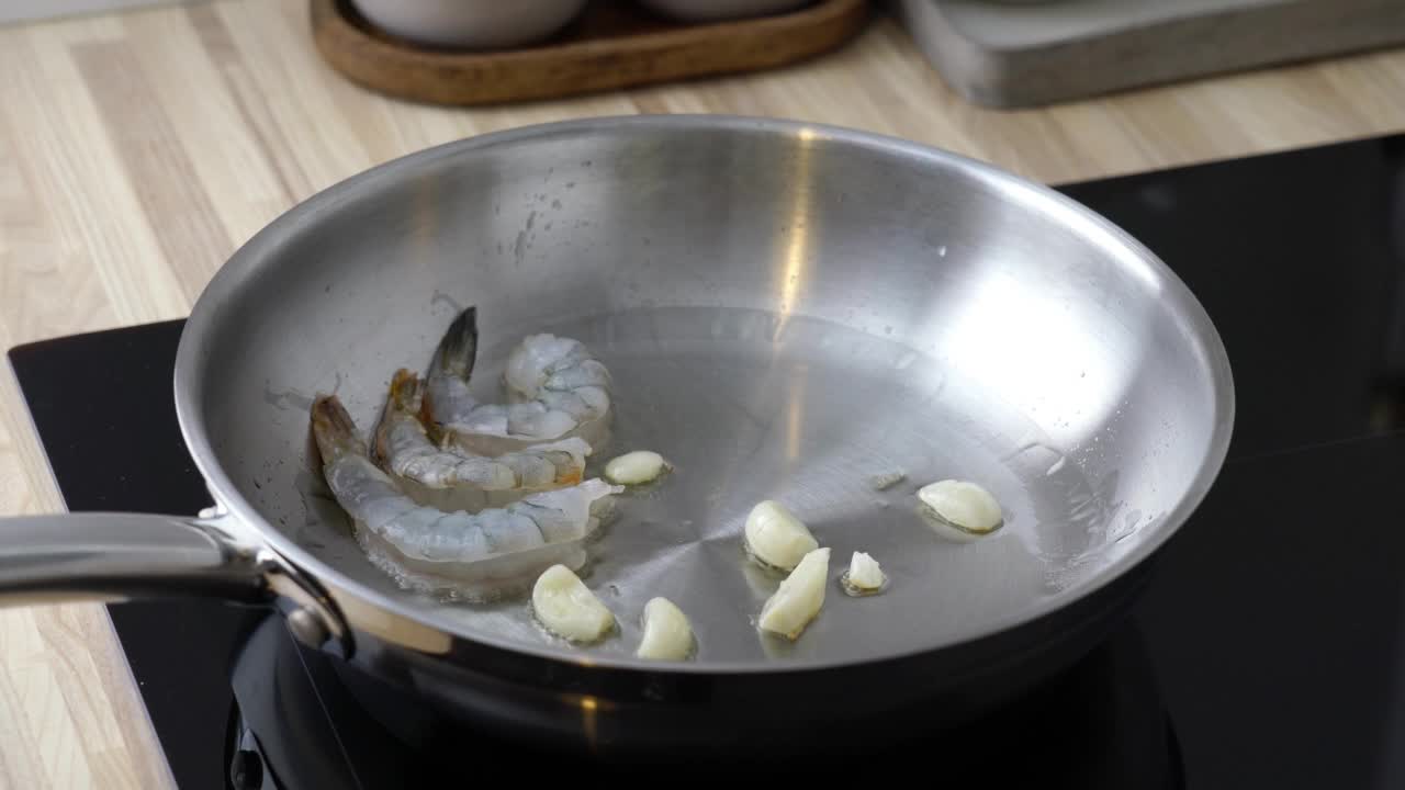 把生虾海鲜放在锅里的人。生酮餐炸虾生酮饮食，准备酱料意大利面，海鲜虾在金属煎锅中滋滋作响，热平底锅油炸富含胆固醇的旧石器食物视频下载