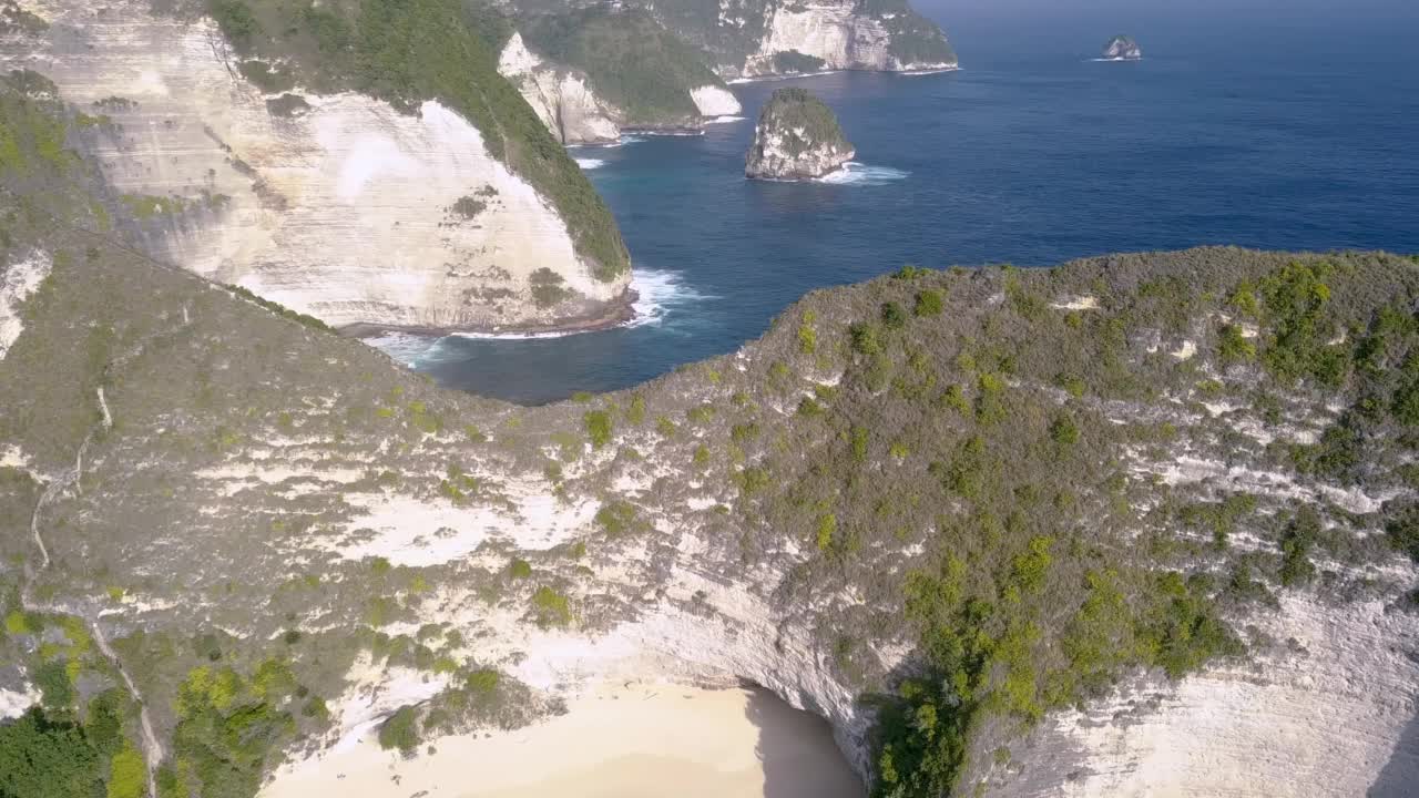 从上到下的无人机鸟瞰努沙佩尼达岛的克林金海滩，美丽的海洋，碧蓝的海浪和山脉。印尼巴厘岛。倾斜无人机在岸上拍摄。霸王龙恐龙悬崖。视频素材