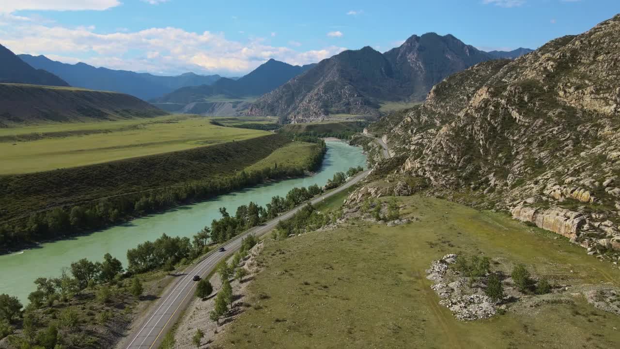 空中:蓝绿色的河流在山谷中流动，道路上有汽车视频素材