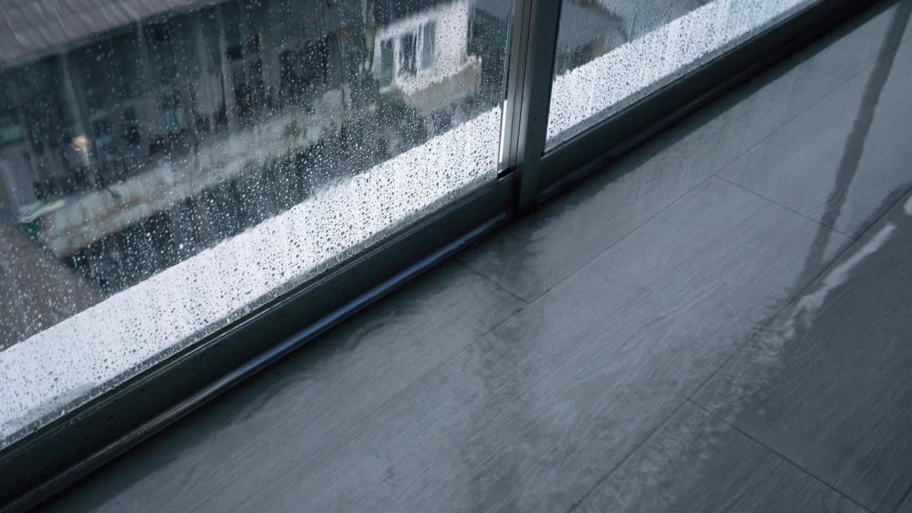 多雨的天气。雨水落在阳台上，顺着玻璃流下视频素材