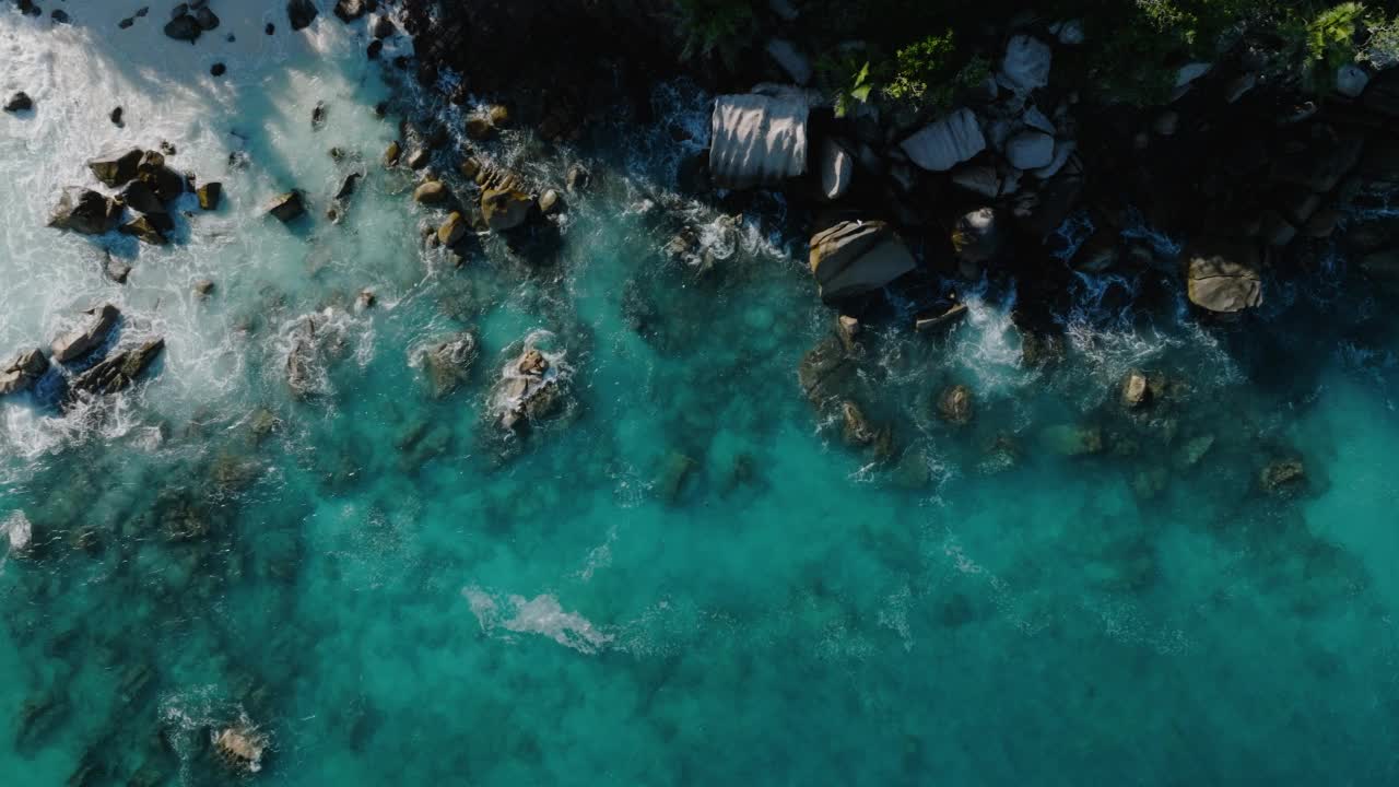 俯瞰鸟瞰图，在美丽的热带岛屿海滩上，海鸟在飞翔，蓝绿色的海浪拍打着岩石视频素材