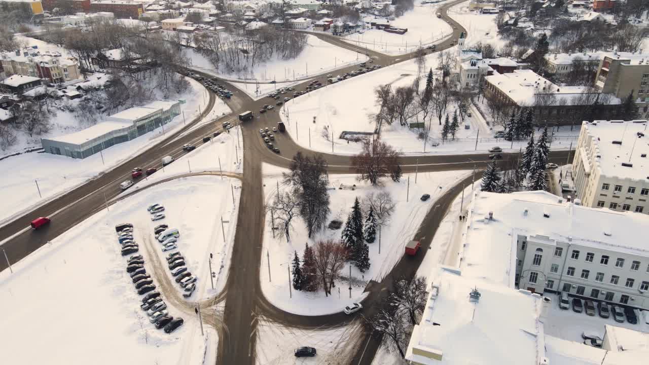 鸟瞰被积雪覆盖的城市十字路口，在冬天行驶的汽车视频素材