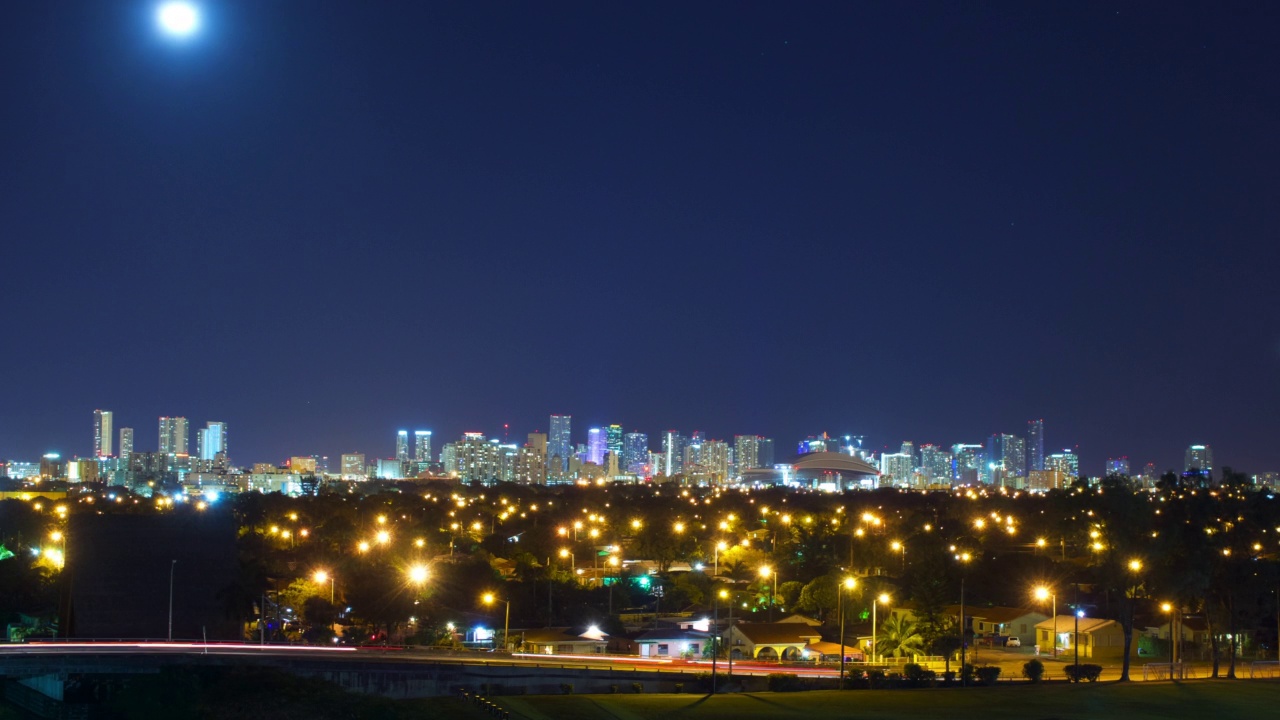 夜晚，当月亮从熙熙攘攘的城市天际线上升起时，时间流逝锁定了它——佛罗里达州的迈阿密视频素材