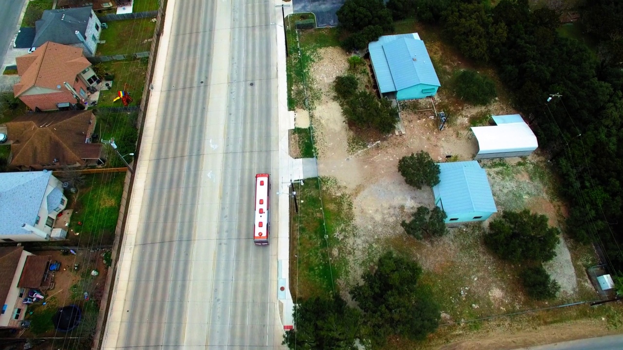 空中拍摄的旅游巴士驶过住宅，无人机在城市道路上向前飞行-圣安东尼奥，德克萨斯州视频素材