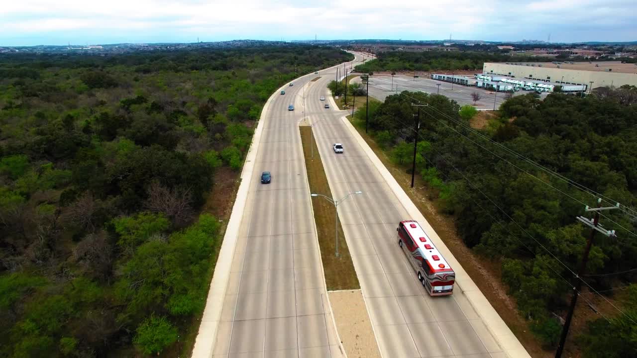 空中拍摄的豪华长途汽车在道路上行驶，无人机在城市的云层下向前飞行-圣安东尼奥，德克萨斯州视频素材