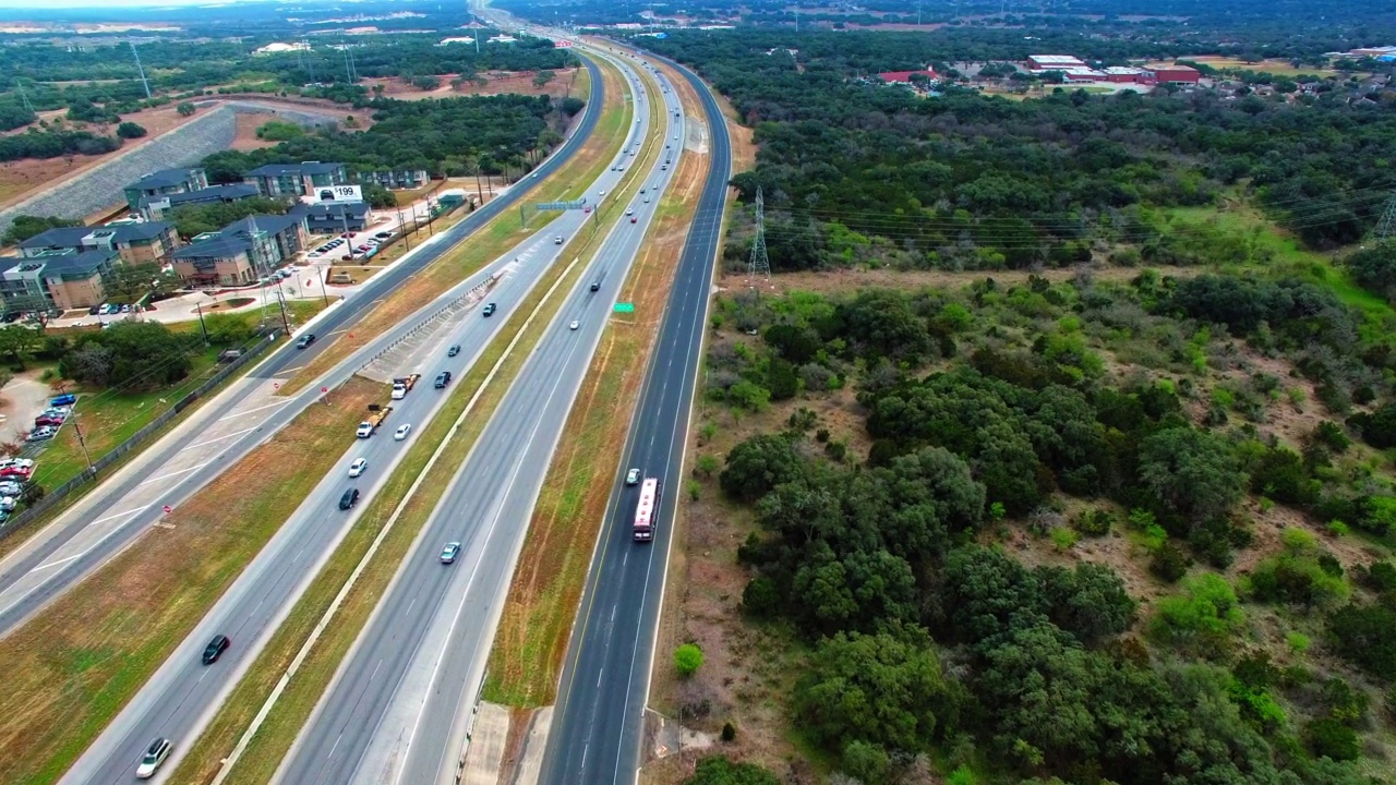 空中向前倾斜拍摄长途汽车和汽车行驶在道路上的绿色植物-圣安东尼奥，德克萨斯州视频素材