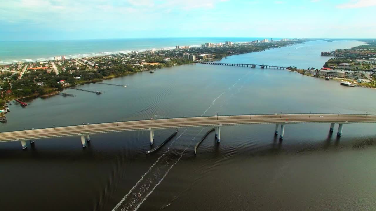 空中拍摄的汽车在多云天空下的城市海上桥上移动-佛罗里达州的代托纳海滩视频素材