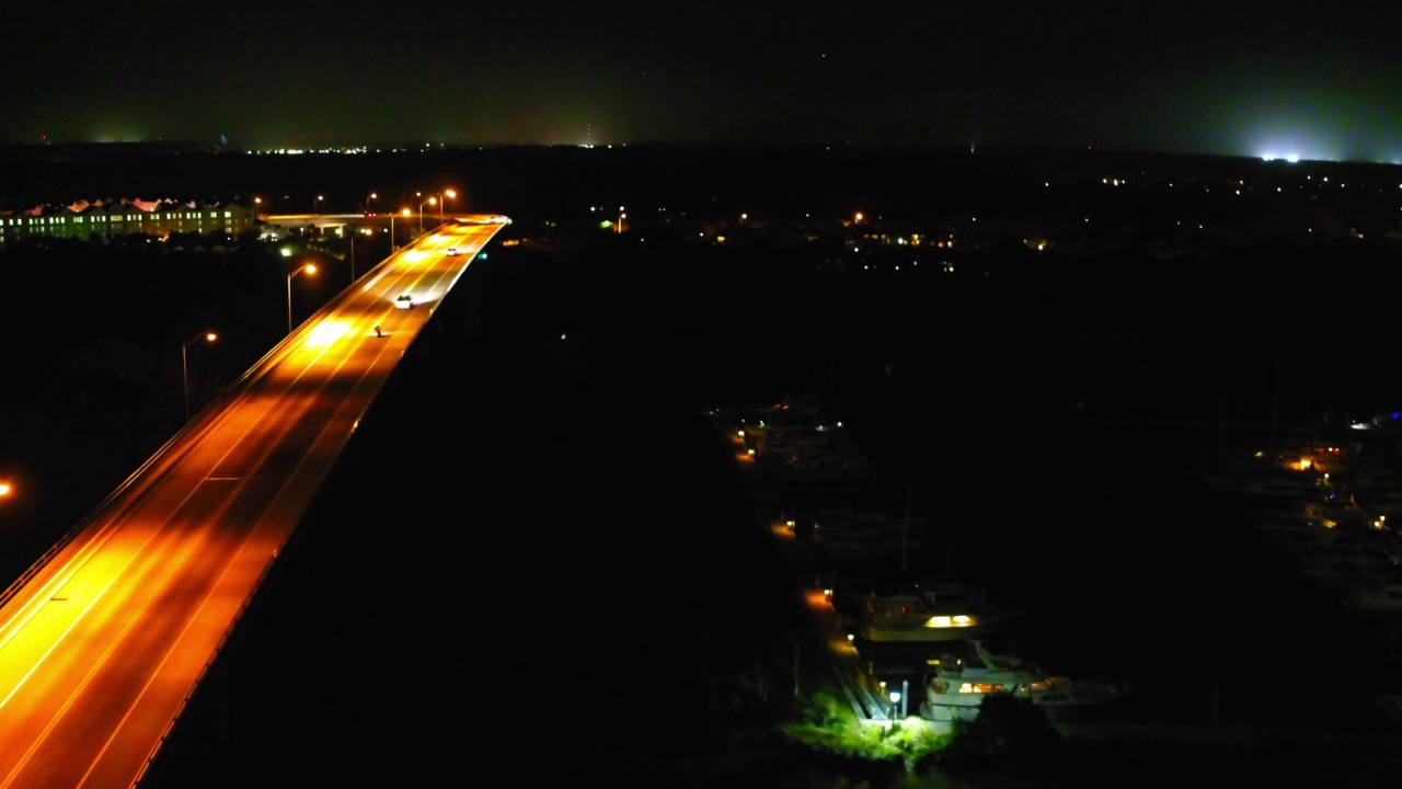 空中向前拍摄的汽车在高速公路上移动与路灯，无人机飞越照亮的城市在夜晚-代托纳海滩，佛罗里达州视频素材