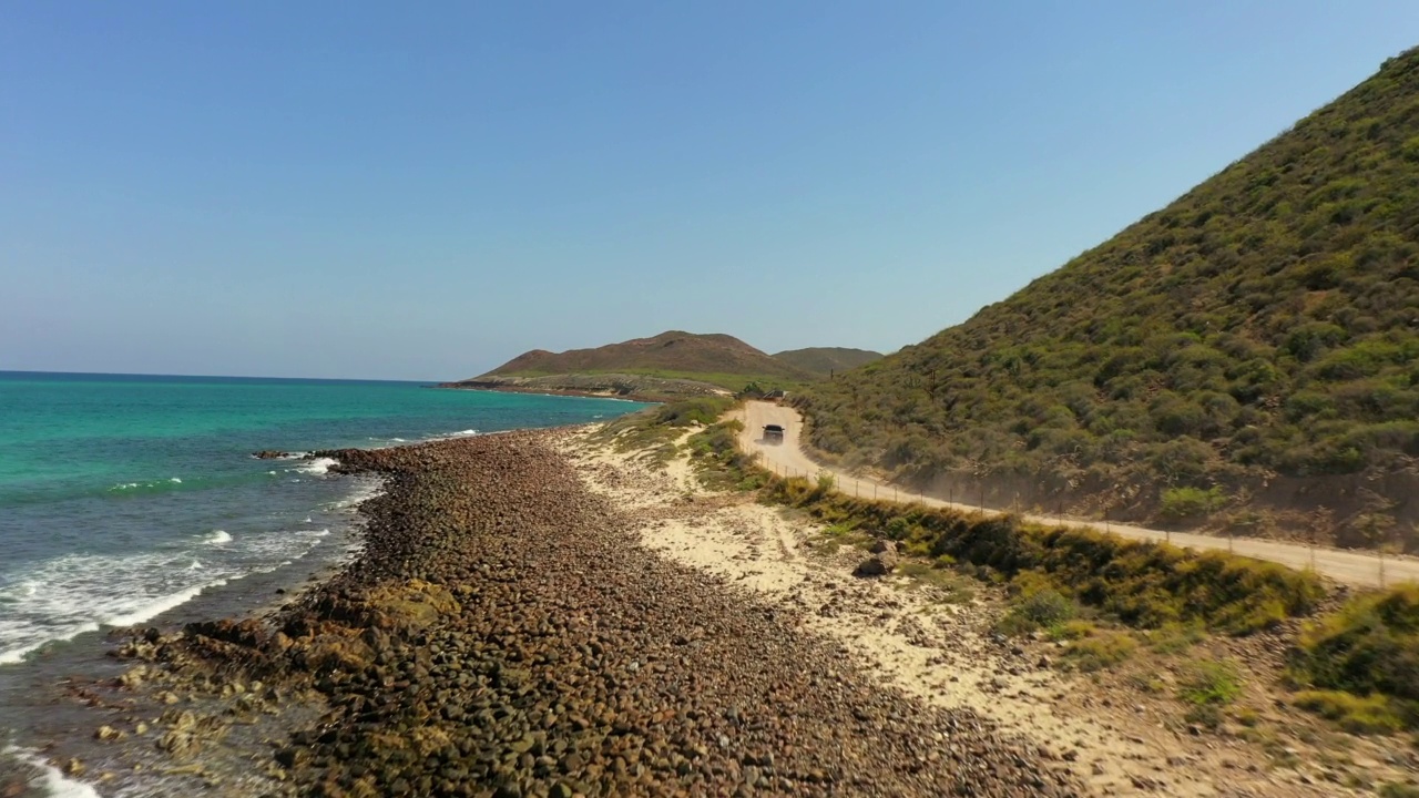 空中向前拍摄的汽车在公路上移动的山在海滩在晴朗的天空-巴哈加利福尼亚州，墨西哥视频素材