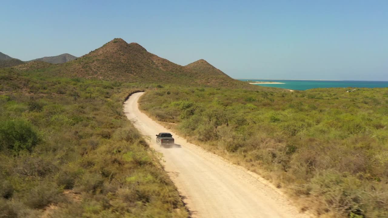 空中拍下美丽的风景，汽车移动在道路上的海滩，无人机飞过植物在阳光灿烂的日子-巴哈加利福尼亚州，墨西哥视频素材