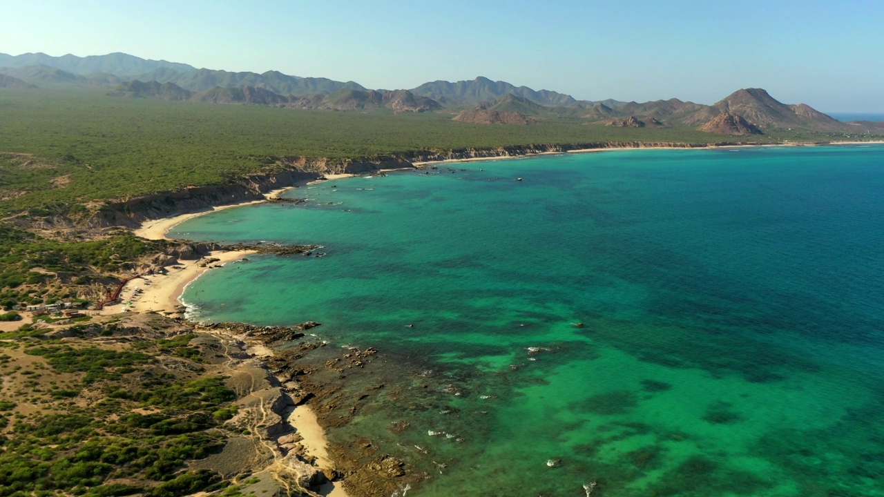 空中向前拍摄的蓝绿色海岸的山对晴空，无人机向前飞过悬崖在海滩-巴哈加利福尼亚州，墨西哥视频素材