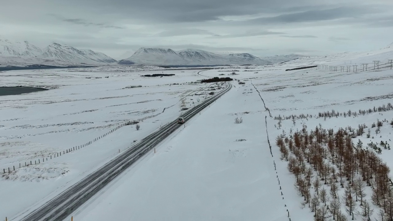 航拍的房车移动在山路上，无人机向前飞越雪景-瓦特纳冰盖国家公园，冰岛视频素材