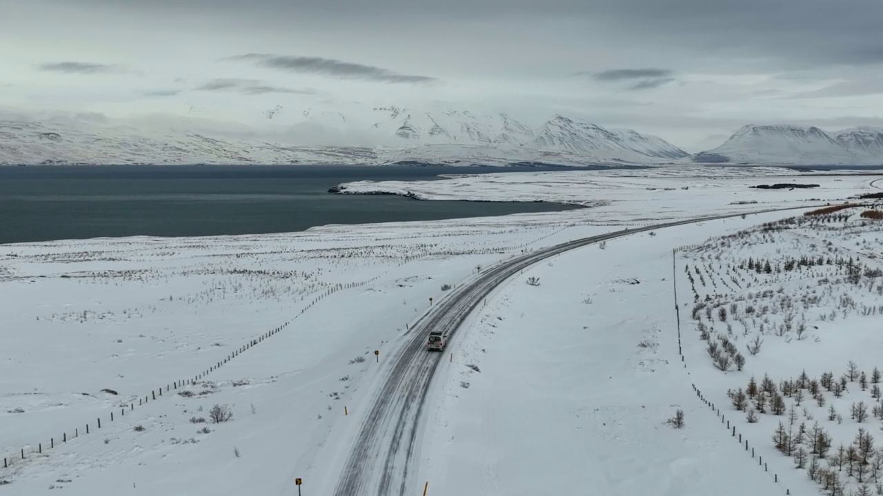 航拍的露营车在海上的道路上移动，无人机在雪景上向前飞行-冰岛的瓦特纳冰盖国家公园视频素材