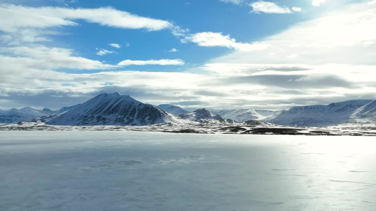 云层下雪山的空中拍景，晴朗的日子无人机飞过结冰的海面-冰岛瓦特纳冰盖国家公园视频素材