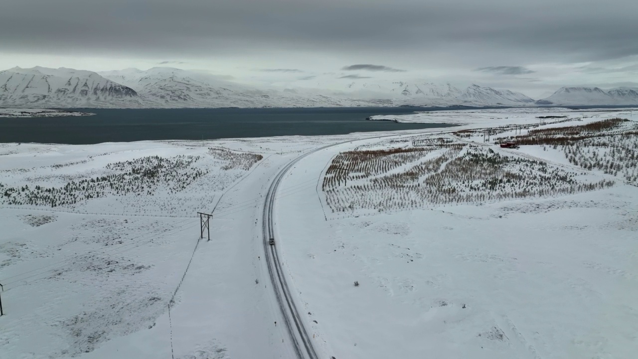 航拍的房车移动在海上的道路上，无人机向前飞越雪景-瓦特纳冰盖国家公园，冰岛视频素材