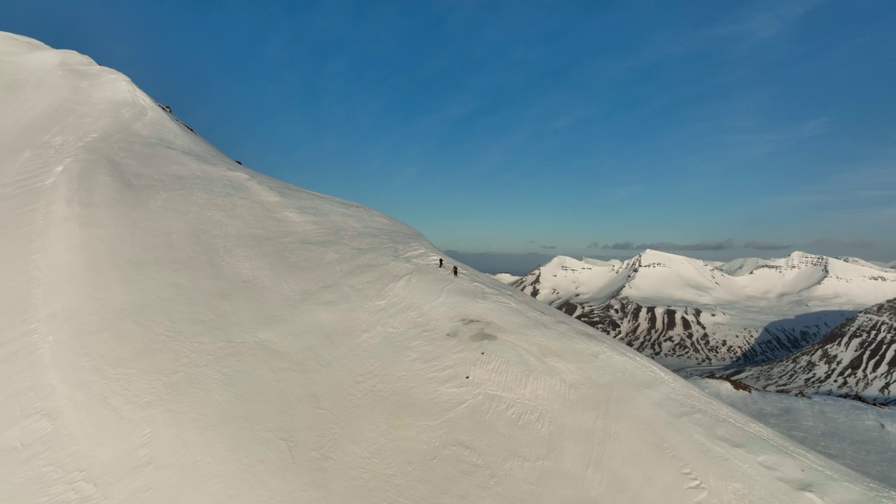 空中拍摄冒险者在雪山上滑雪，无人机在阳光明媚的日子向前飞行-冰岛的瓦特纳冰川国家公园视频素材