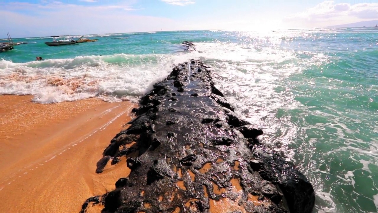 在阳光明媚的日子里，海浪溅在大海中的岩石上的慢动作镜头——夏威夷的威基基视频素材