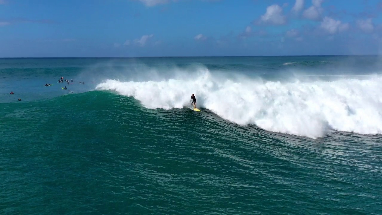 空中拍摄的冲浪者在云层下的海浪上冲浪，无人机在阳光灿烂的日子向后飞行-怀基基，夏威夷视频素材