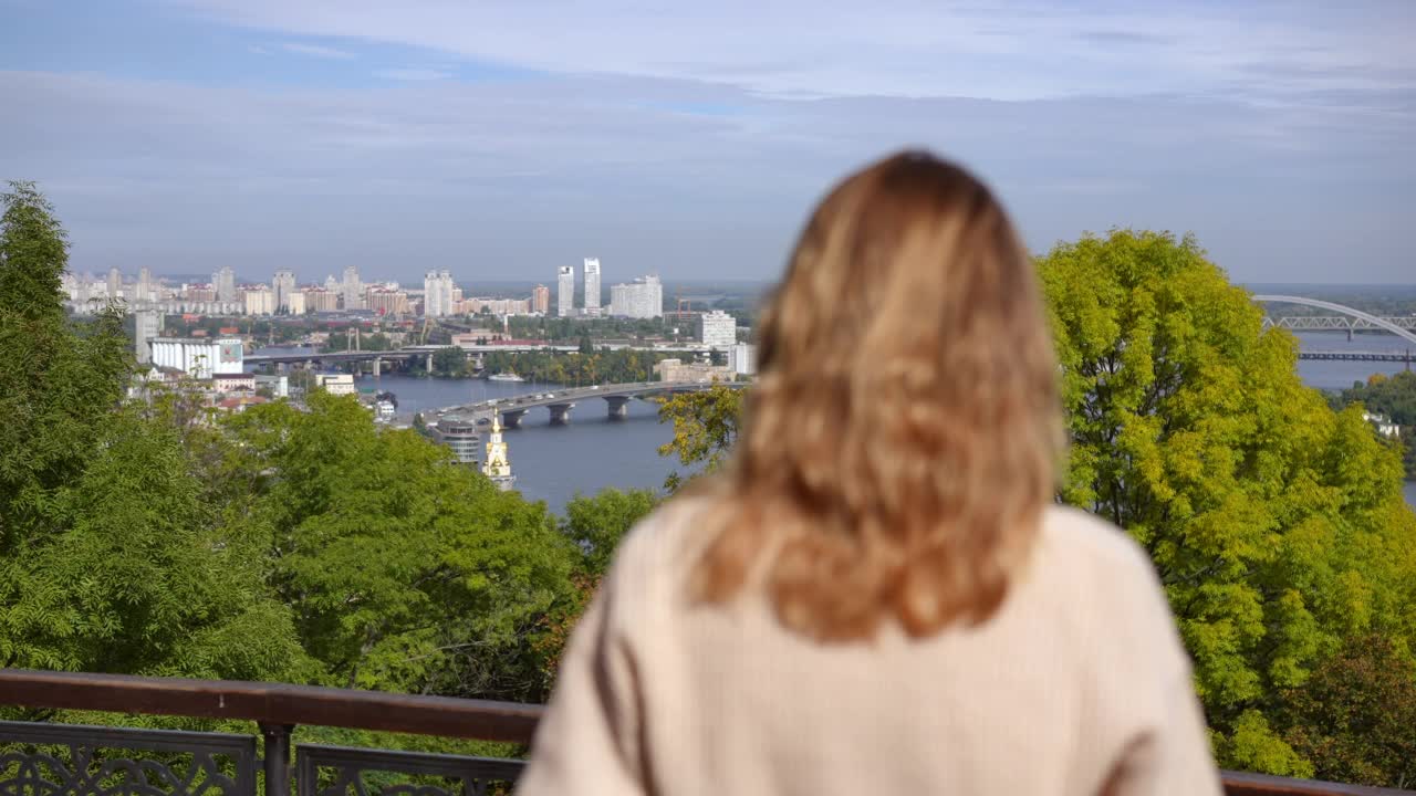 河岸上的城市，桥上的汽车和模糊的年轻女子举起手在前面的慢动作。快乐、轻松、无忧无虑的白种女子，周末在户外享受秋天的闲暇。视频素材