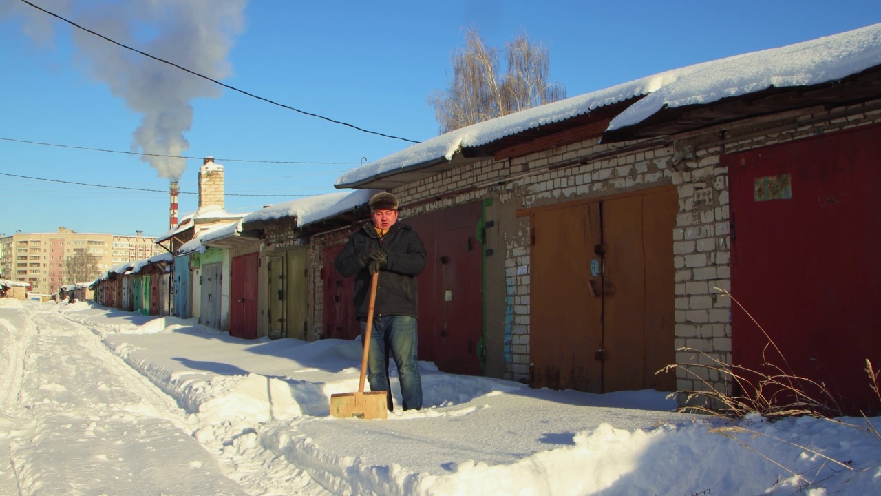 一名男子愉快地用木铲清理通往车库的积雪通道视频素材