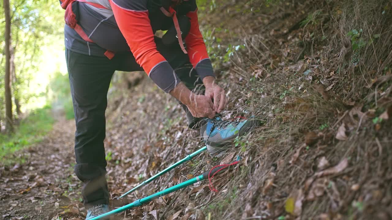 高级男性在山上徒步时休息和系鞋带视频素材