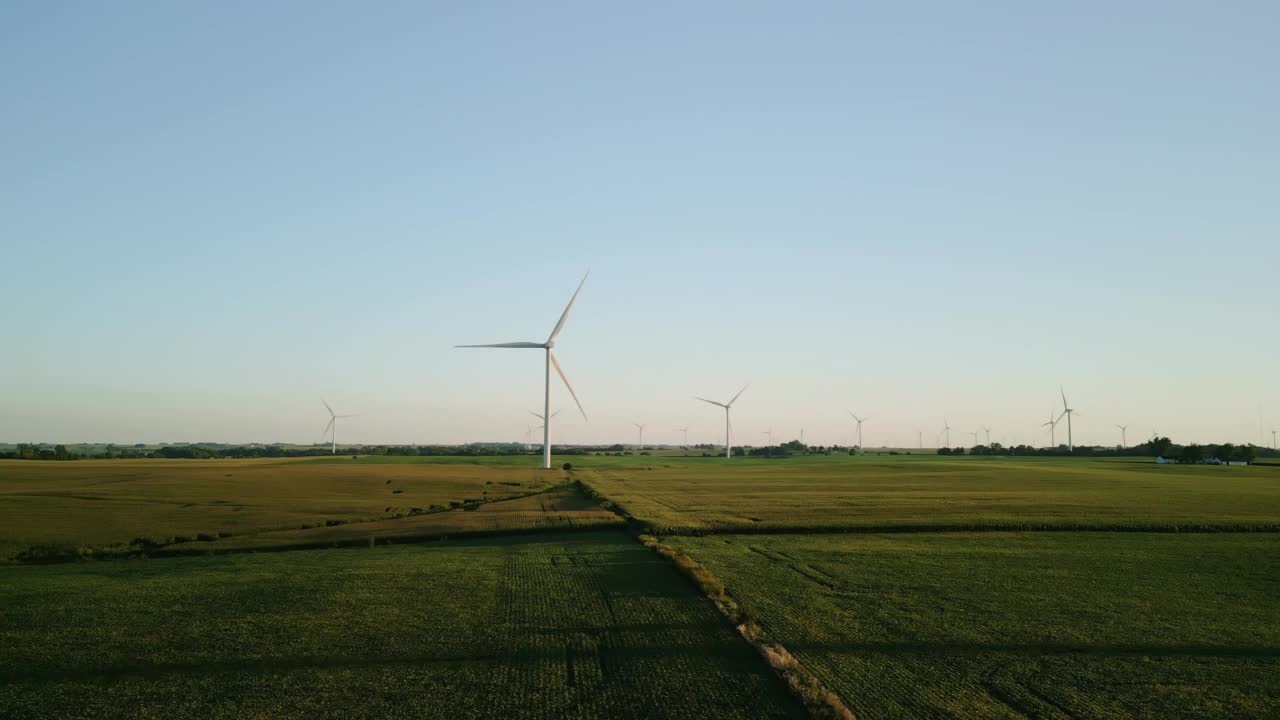 空中广视图。夕阳下的麦田里，矗立着风力涡轮机的风电场公园。移动镜头视频素材