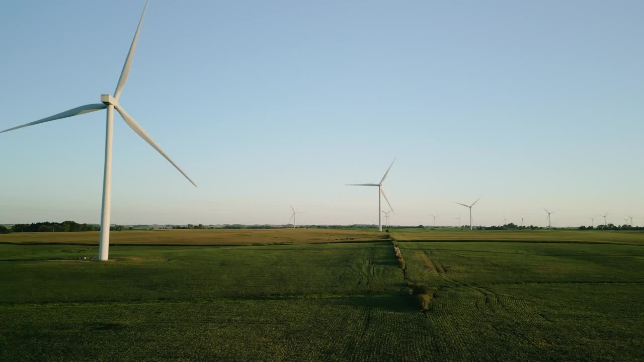 空中广视图。夕阳下的麦田里，矗立着风力涡轮机的风电场公园。移动无人机画面视频素材