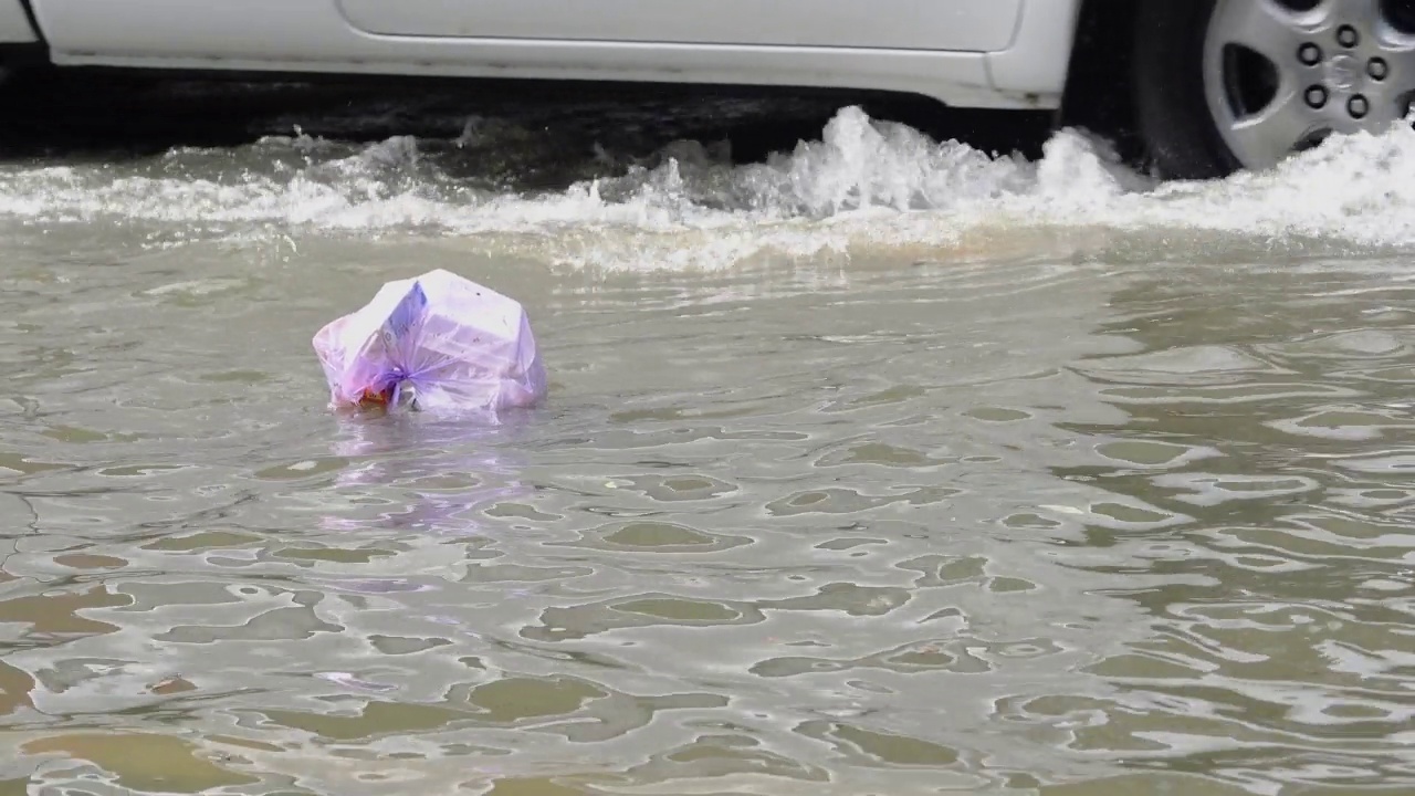 垃圾漂浮在被洪水淹没的道路上。视频素材