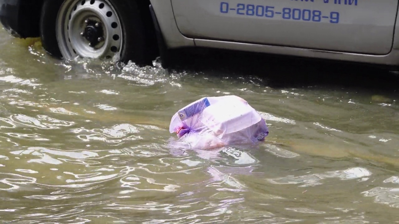 垃圾漂浮在被洪水淹没的道路上。视频素材