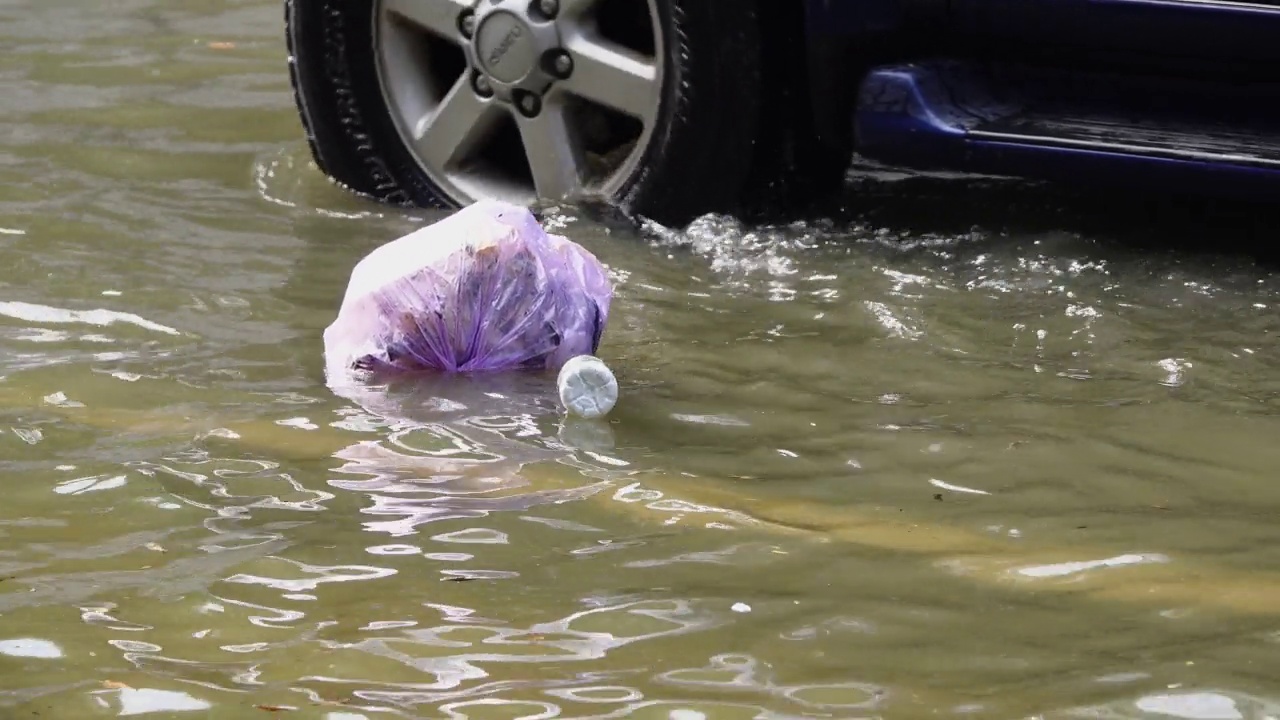 垃圾漂浮在被洪水淹没的道路上。视频素材