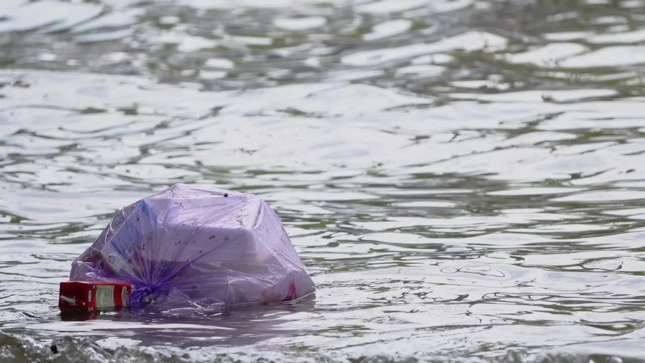 垃圾漂浮在被洪水淹没的道路上。视频素材